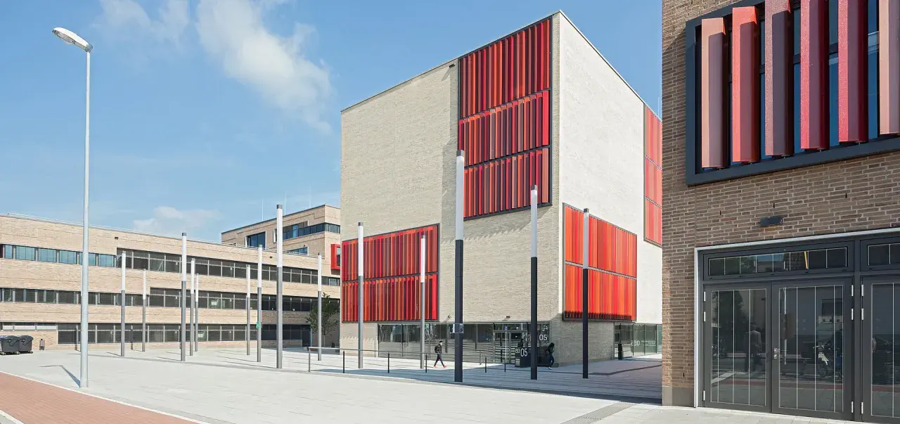 Moderne Gebäude der Hochschule Essen mit hellen Ziegelwänden und auffälligen roten Fassadenelementen.