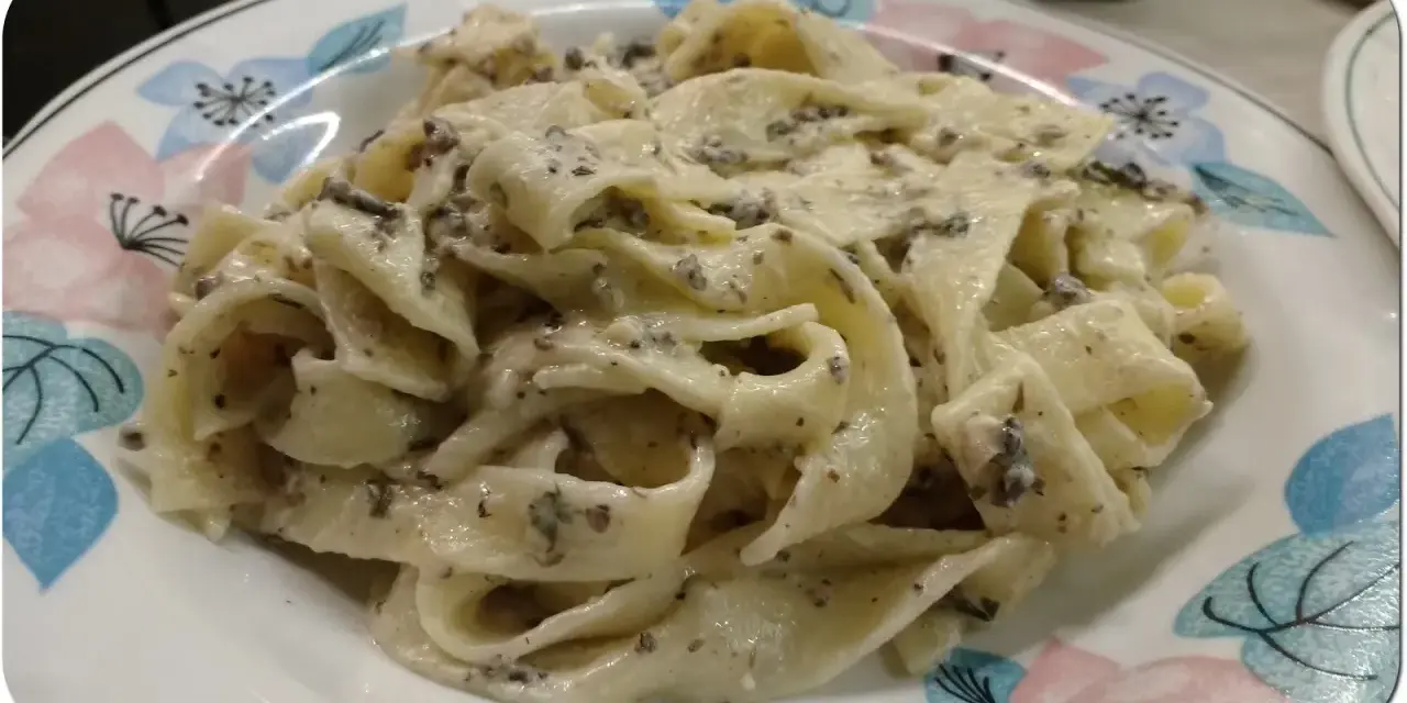 Pappardelle z kremowym sosem z mascarpone i aromatyczną pastą truflową, podane na talerzu z kwiatowym wzorem.