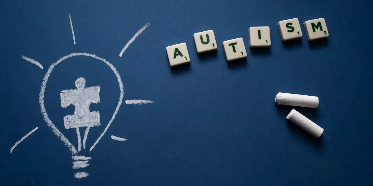 Żarówka z symbolem puzzli i litery tworzące słowo AUTISM. Wiele sławnych osób z autyzmem inspiruje nas każdego dnia.