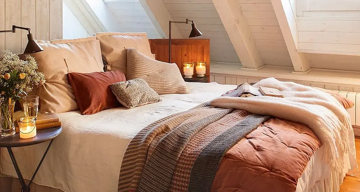 Dormitorios cálidos y acogedores bajo un techo abuhardillado. Cama con mantas de punto y cojines mullidos. Velas y flores crean un ambiente íntimo.