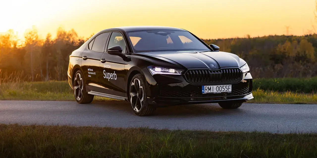 Czarny Skoda Superb 4 na tle zachodzącego słońca. Elegancki sedan z nowoczesnymi światłami i felgami.