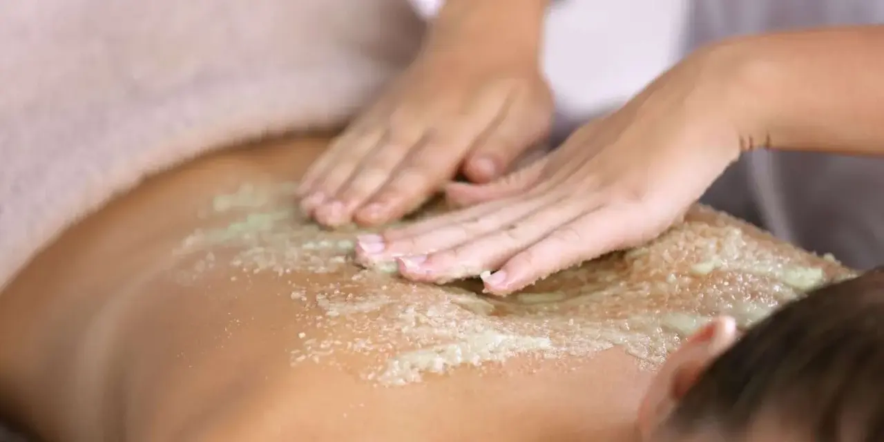 Manos expertas realizan un peeling corporal exfoliante, dejando la piel suave y renovada.