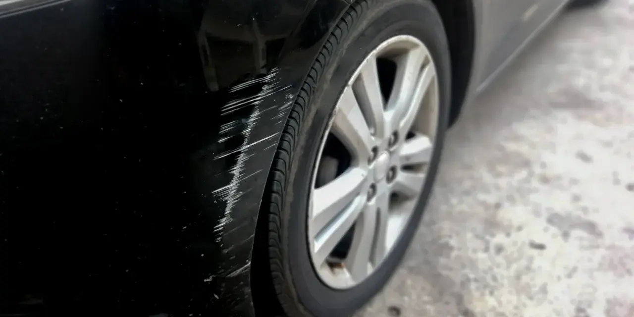 Scratches mar the black paint on a car's fender. Learn how to get scratches out of black car paint to restore its shine.