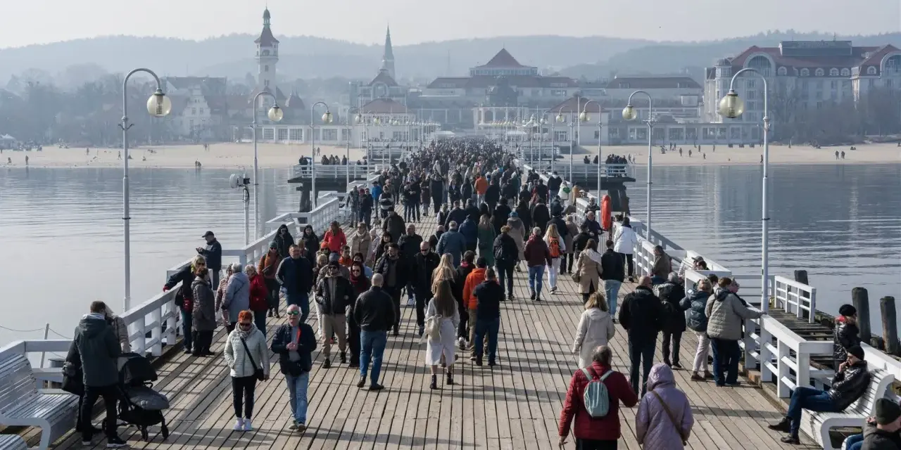 Tłumy ludzi spacerują po drewnianym molo w Sopocie. Czy molo w Sopocie jest płatne? Tego dnia wejście było darmowe, co przyciągnęło wielu turystów.