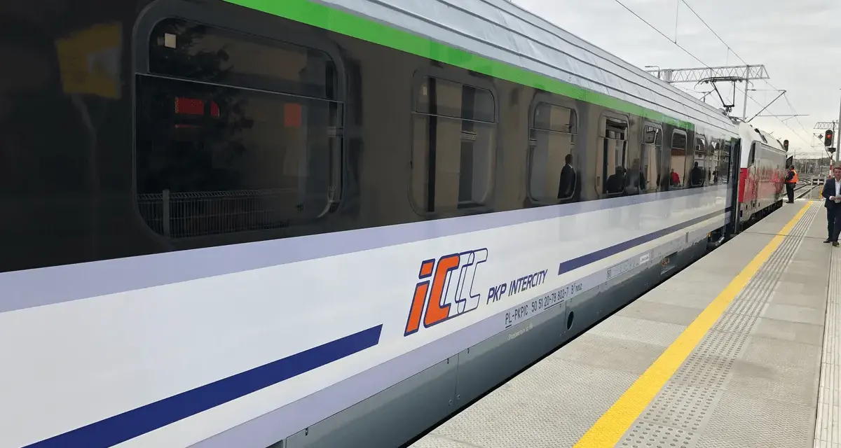 Pociąg PKP Intercity z charakterystycznym logo eic a ic stoi na peronie.