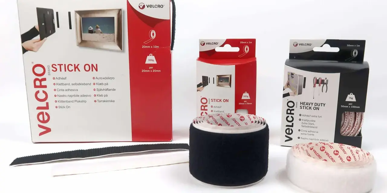 Comment poser du velcro adhésif : démonstration avec des rouleaux et boîtes de différentes tailles pour fixer cadres et outils.