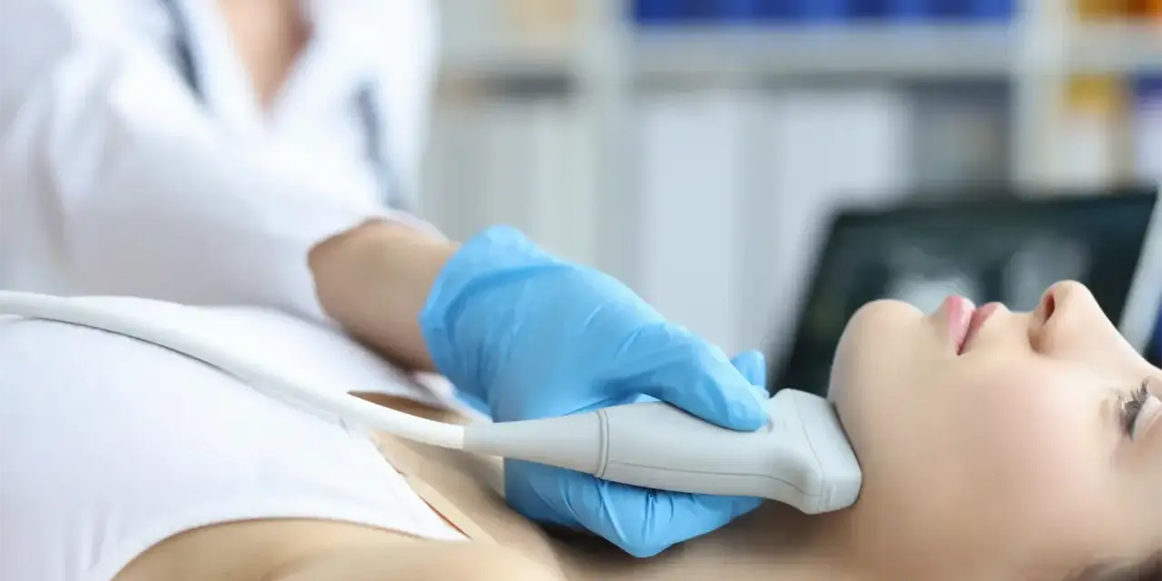 Fizjoterapeuta wykonuje badanie USG szyi, co może być częścią terapii stawu skroniowo-żuchwowego.
