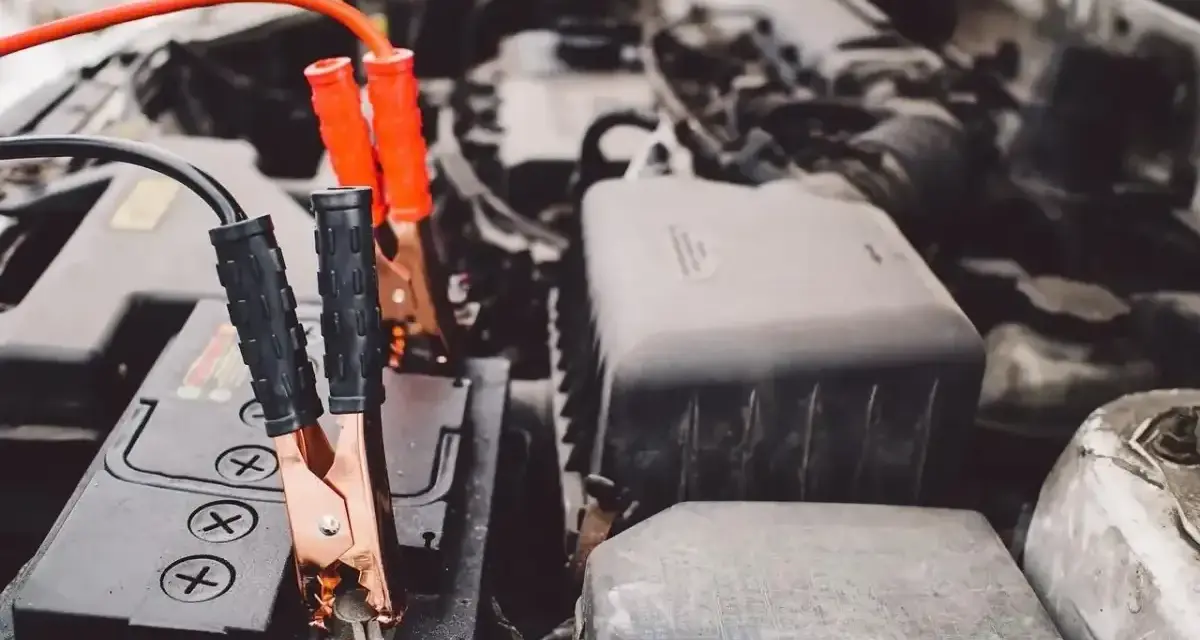 Kable rozruchowe podłączone do akumulatora samochodowego. Wygląda na to, że właśnie ratujemy auto z rozładowanym akumulatorem.