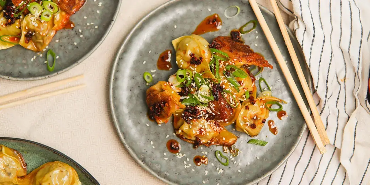 Stekta dumplings med en kryddig sås, toppade med sesamfrön och salladslök. En utsökt dumplings sås som gör rätten komplett.