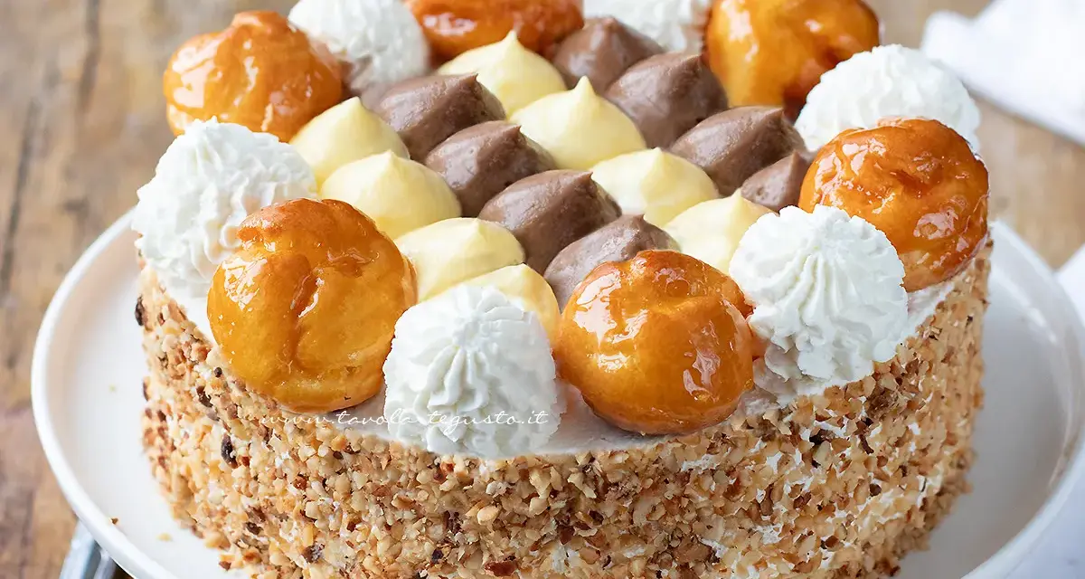 Una deliziosa torta Saint Honoré, con bignè caramellati, panna montata e crema al cioccolato e vaniglia, il tutto ricoperto di granella di nocciole.