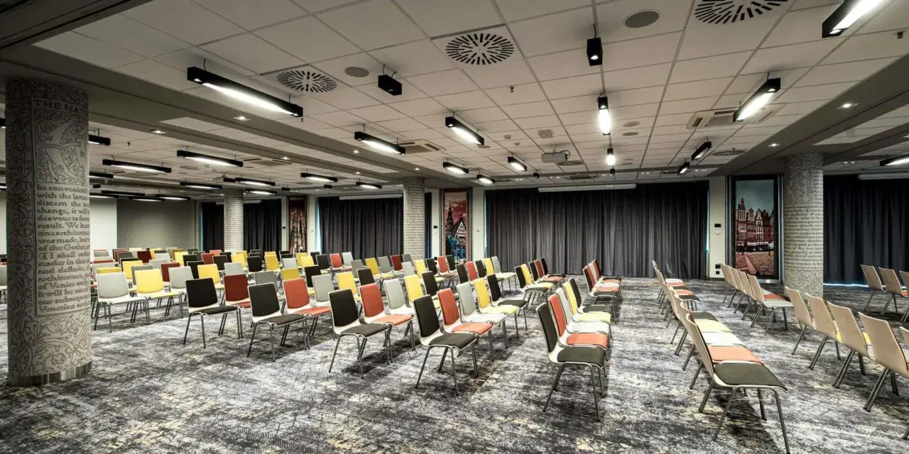 Sala konferencyjna w hotelu Mercure Wrocław, przygotowana na wydarzenie. Rzędy kolorowych krzeseł czekają na gości.