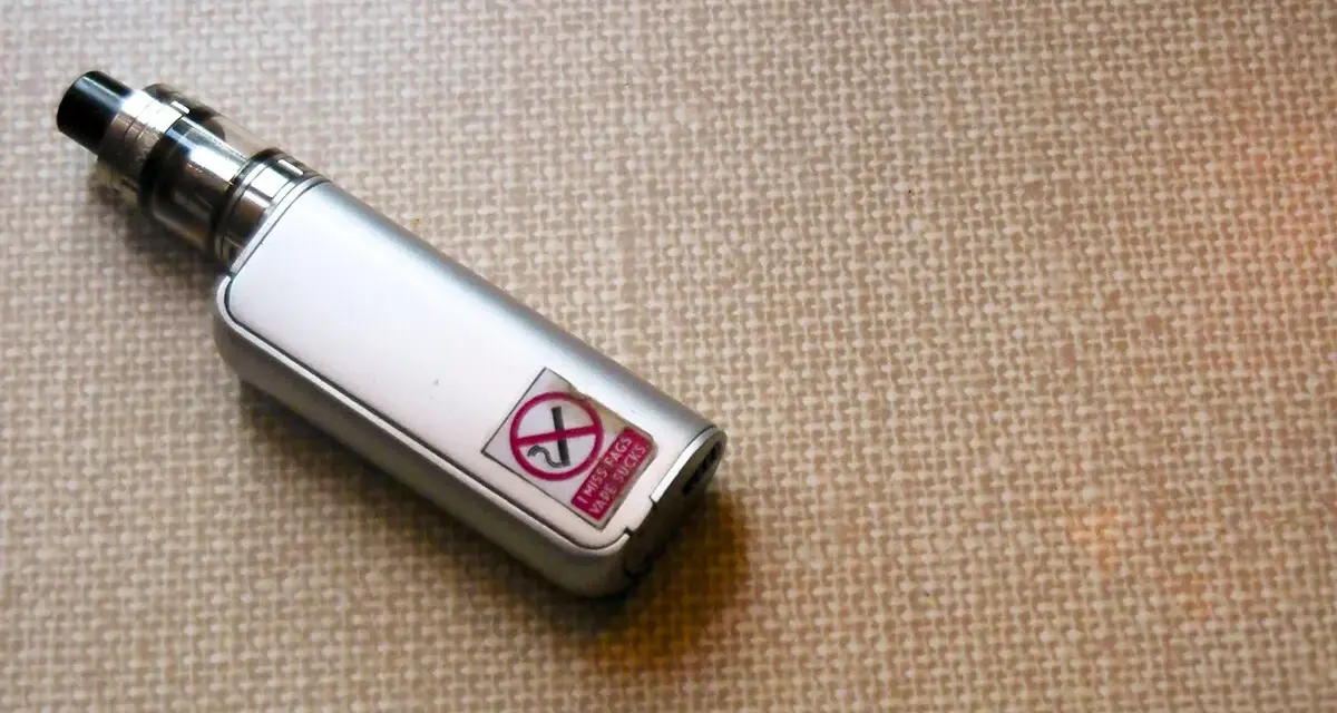 Un vape plateado con una pegatina que dice "I MISS FAGS VAPE SUCKS" y un símbolo de prohibido.