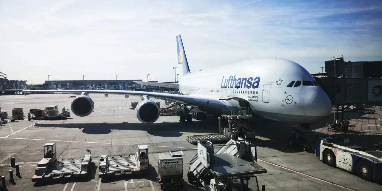 Lufthansa A380 na płycie lotniska we Frankfurcie. W tle widać inne samoloty i budynki terminali, typowe dla lotnisk w Niemczech.