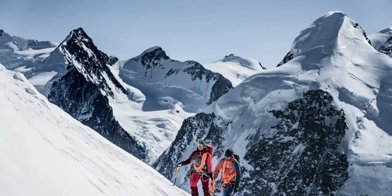 Zwei Bergsteiger, ein beal escaper-Team, steigen einen schneebedeckten Hang hinauf, umgeben von majestätischen, eisigen Gipfeln.