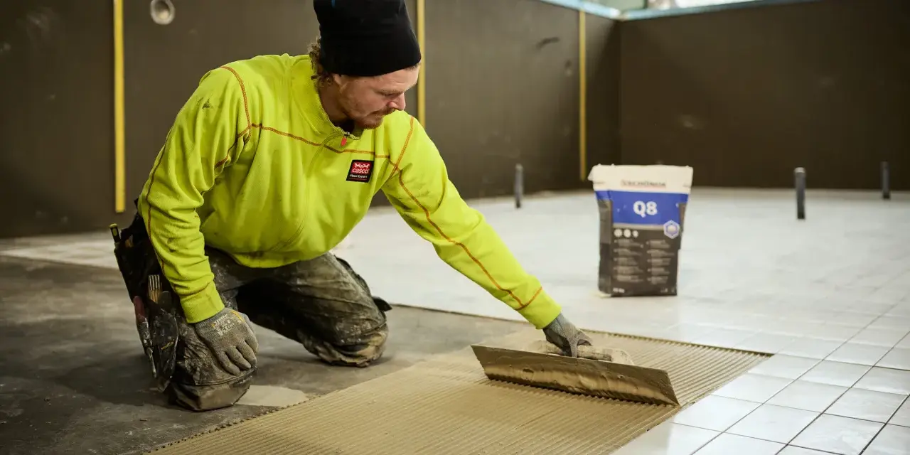 Man i gul jacka lägger fix på golvet för att byta ut det.