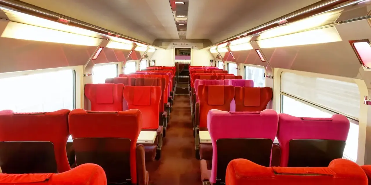 Rows of red and pink seats inside a train car, ready for passengers on the best train from Amsterdam to Paris.
