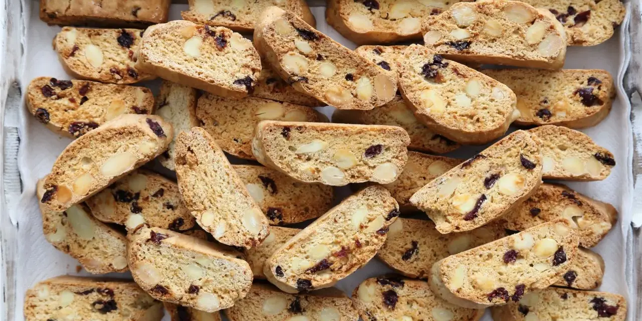 Un vassoio pieno di croccanti biscotti toscani, ricchi di mandorle e mirtilli rossi, pronti per essere inzuppati.