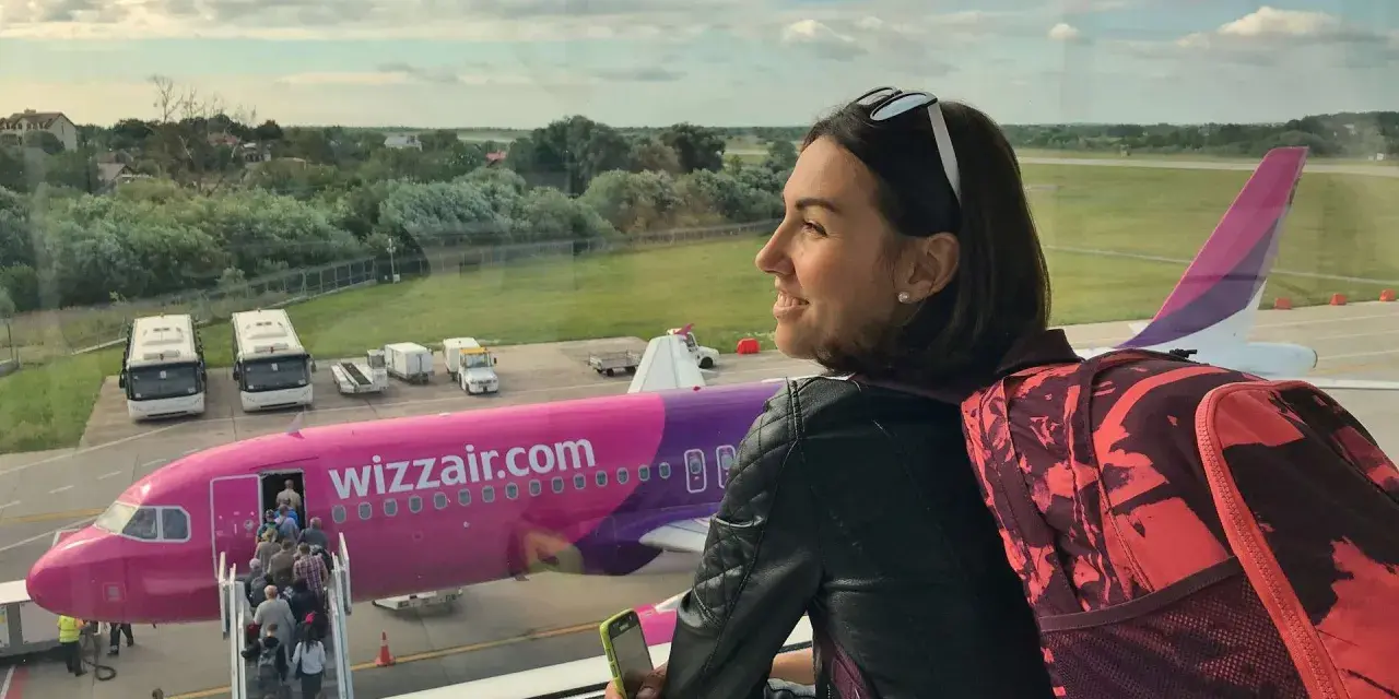 Kobieta z plecakiem czeka na lot Wizzair. W samolocie można zabrać podręczny bagaż, np. plecak i telefon.