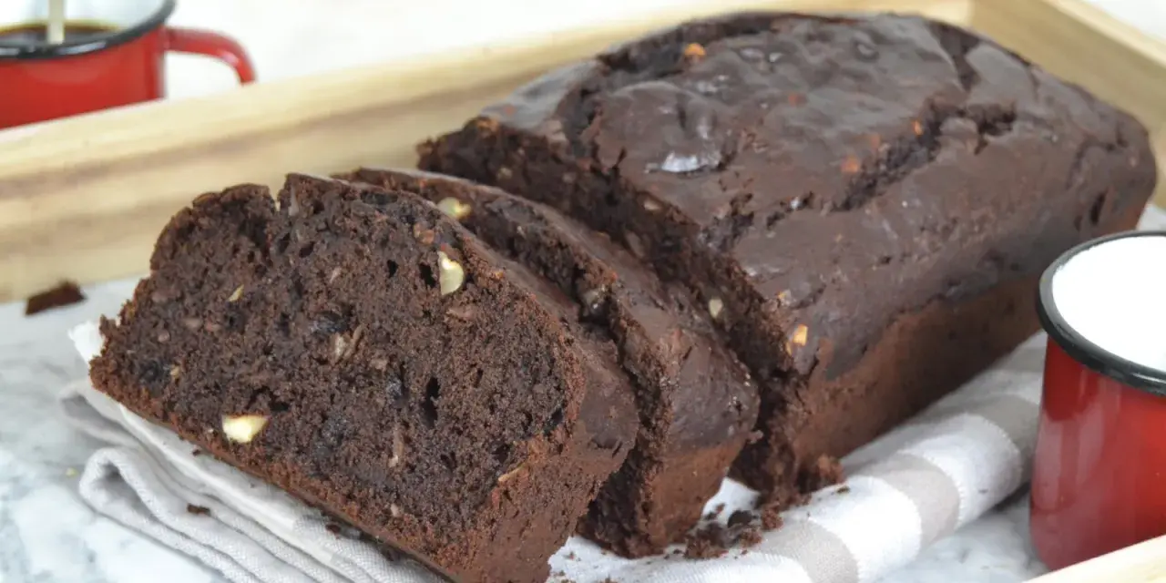 Bizcocho de platano y chocolate, recién horneado y cortado en rebanadas, con trozos de nuez visibles.