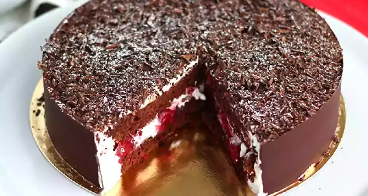 Tarta Selva Negra, con capas de bizcocho de chocolate, nata montada y cerezas, cubierta de virutas de chocolate y un toque de azúcar glas.