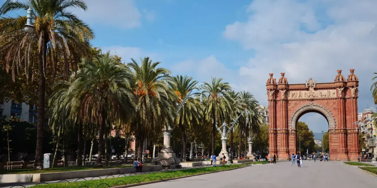 Łuk Triumfalny w Barcelonie, z rzędem palm i błękitnym niebem, to ikoniczne miejsce, które podkreśla wspaniałe barcelona położenie.
