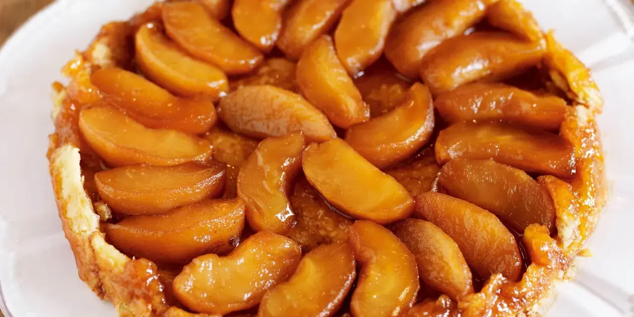 En gyllene tarte tatin med karamelliserade äppelklyftor som glänser. En klassisk fransk dessert som smälter i munnen.