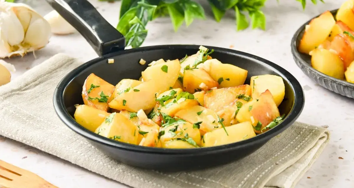 Patatas al ajillo recién hechas en sartén, con perejil fresco y ajos picados. ¡Un plato sencillo y delicioso!