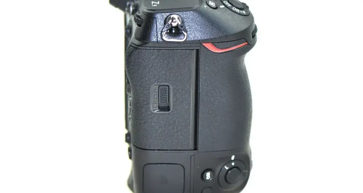 Boczny widok aparatu Nikon Z9, gotowego do testów. Widoczny slot na kartę pamięci i przyciski sterujące.