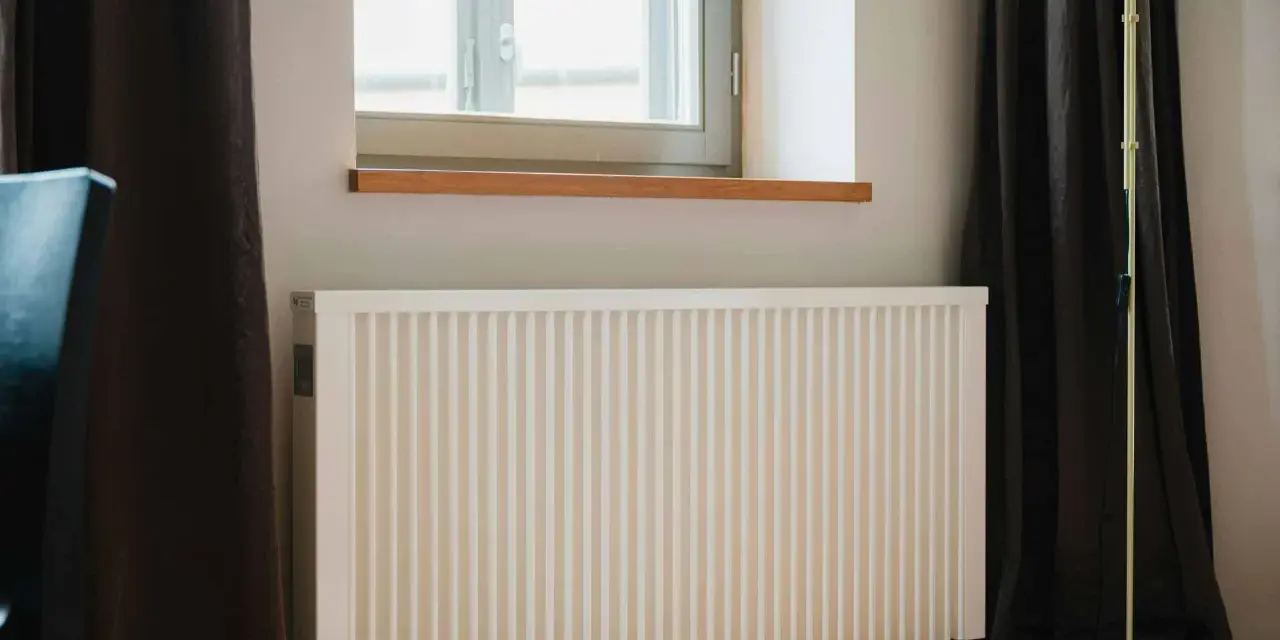 Radiateur électrique blanc moderne près d'une fenêtre. Idéal pour bénéficier de l'aide de l'état pour changer radiateur électrique.
