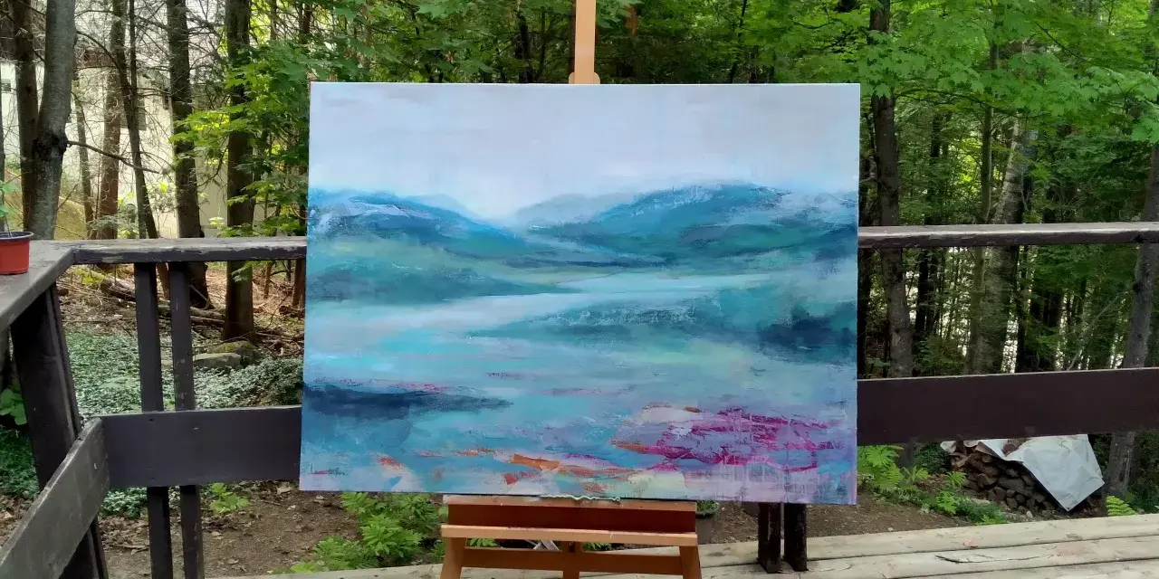 Un paysage abstrait aux teintes bleues et vertes, évoquant des montagnes brumeuses et un lac. Le fond de tableau peinture est posé sur un chevalet, en extérieur, entouré de verdure.