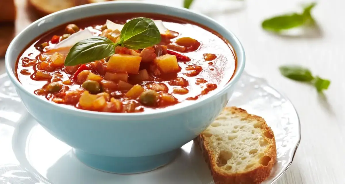 Aksamitna zupa solferino w błękitnej miseczce, ozdobiona bazylią i parmezanem, podana z chrupiącą grzanką.