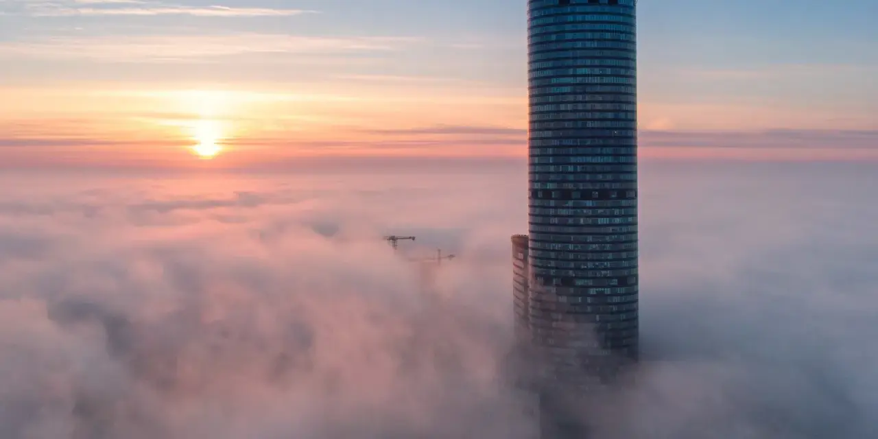 Sky Tower Wrocław, jego imponująca wysokość ginie we mgle o wschodzie słońca. Widok zapiera dech.