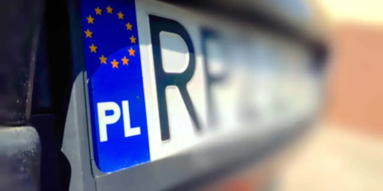 Zbliżenie na polską tablicę rejestracyjną z symbolem UE. Litery "PL" i fragment numeru rejestracyjnego są wyraźne.