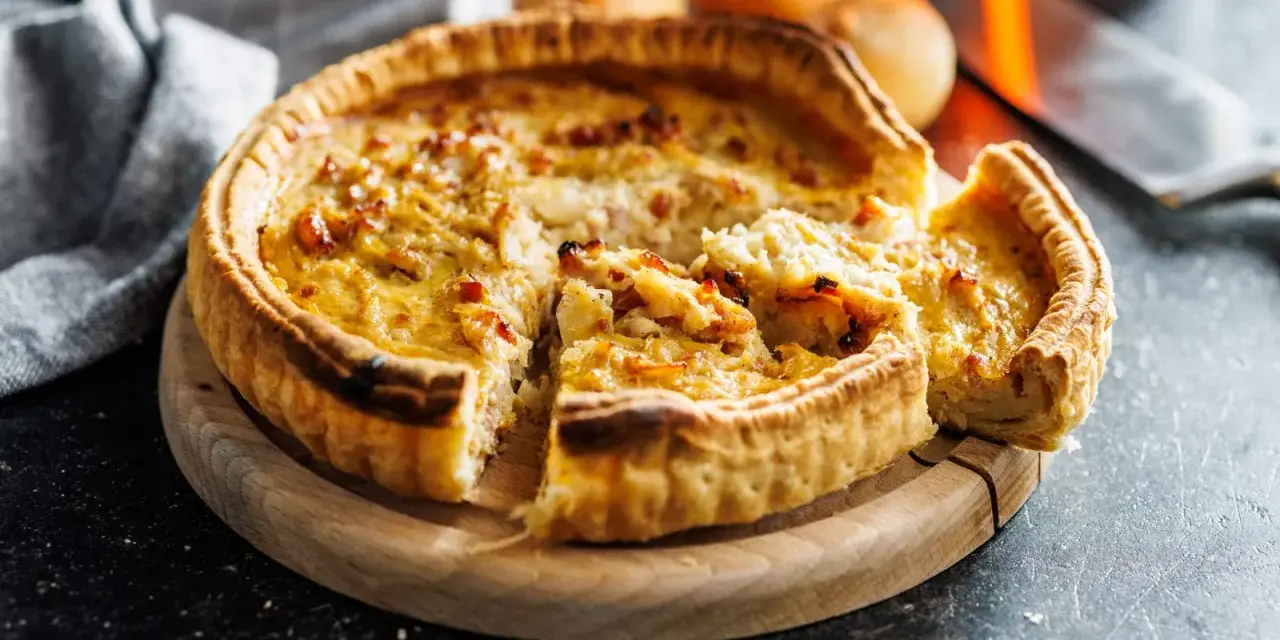 Une quiche lorraine dorée, prête à être dégustée. La cuisson est parfaite, la pâte croustillante et la garniture onctueuse.