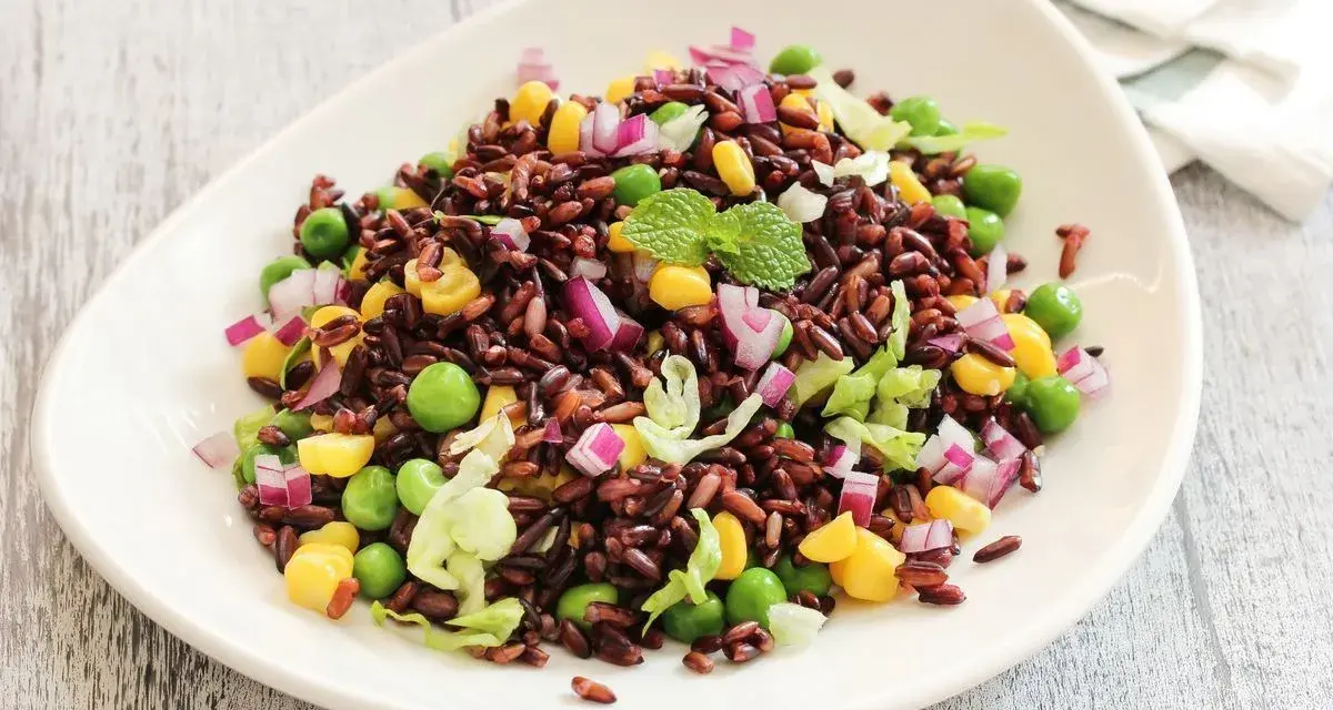 Insalata colorata con riso venere, piselli, mais, cipolla rossa e lattuga. Un'idea fresca per le tue riso venere ricette.