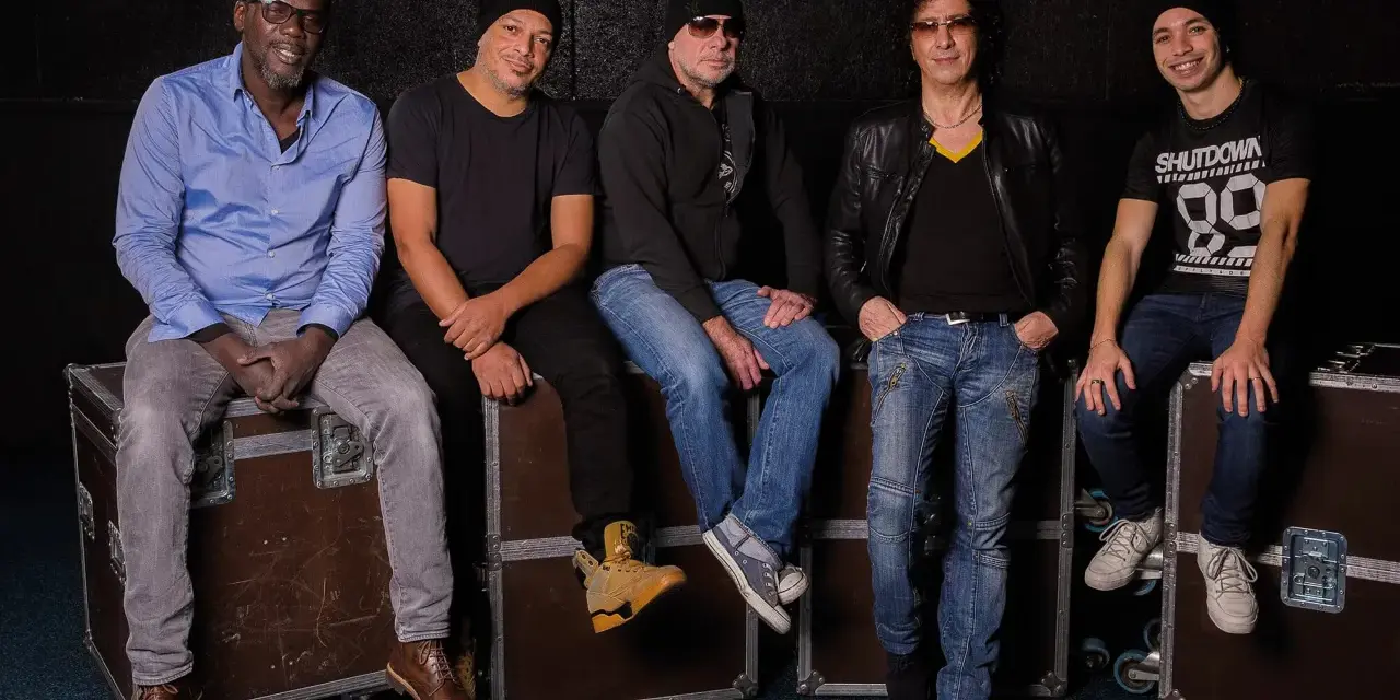 Les membres de Trust (groupe) posent ensemble, assis sur des flight cases, prêts pour leur prochaine performance.