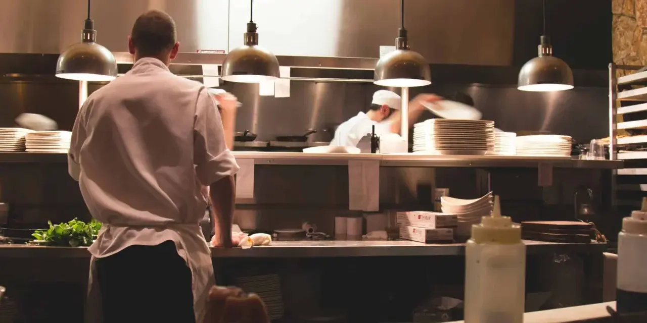 Kucharz w białej koszuli i fartuchu pracuje w kuchni restauracyjnej. To idealne miejsce, by napisać list motywacyjny kucharz.