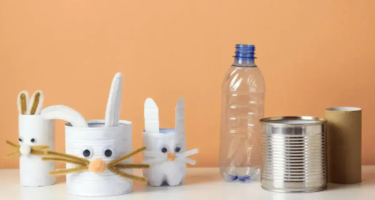 Zające z rolek po papierze i puszek to świetne przykłady recyklingu w życiu codziennym. W tle pusta butelka i rolka po ręczniku papierowym.