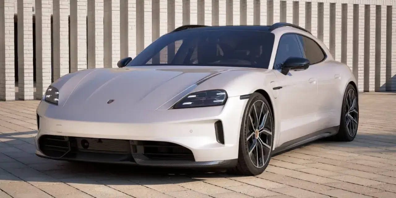 Elegancki Porsche Taycan w kolorze jasnoszarym, zaparkowany przed nowoczesnym budynkiem. Sprawdź porsche taycan cena!