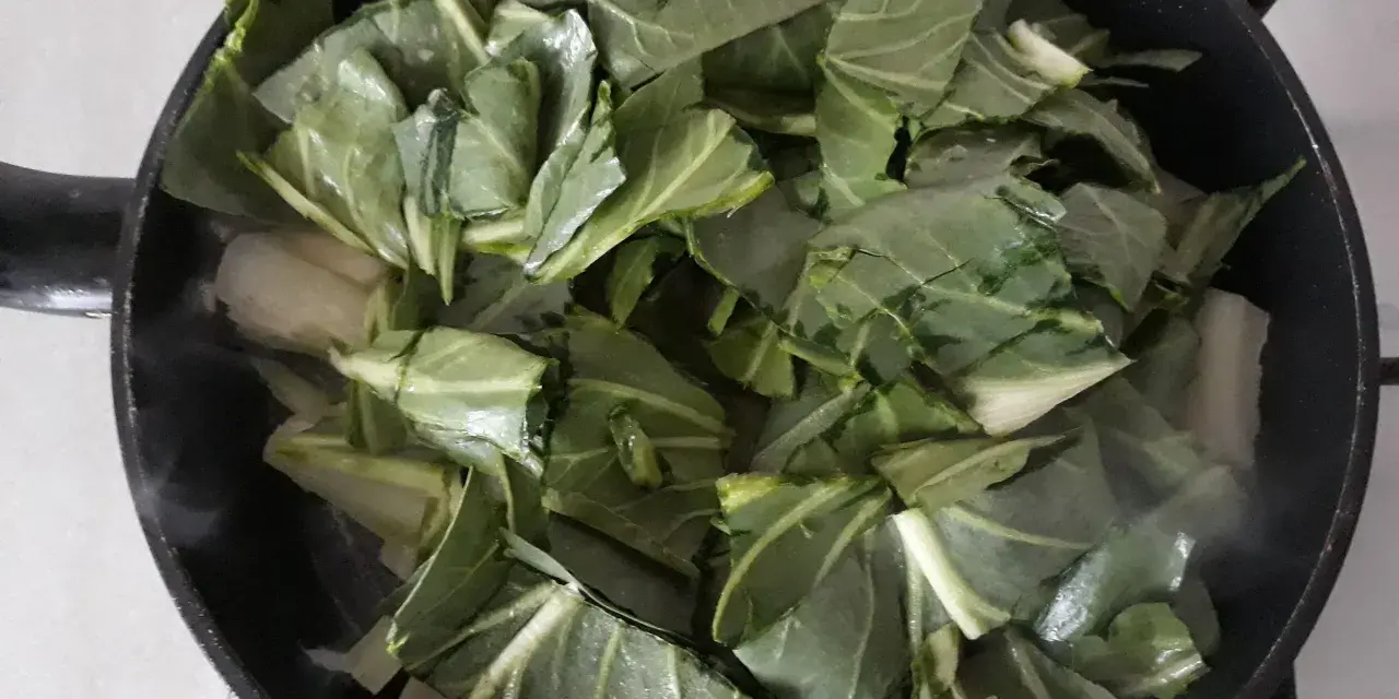 Verdure a coste in padella, che rilasciano vapore mentre cuociono.