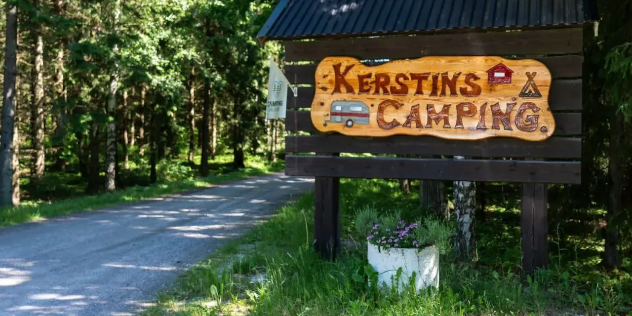 Välkommen till Kerstins Camping! En skylt i trä visar vägen till en lugn plats i skogen.