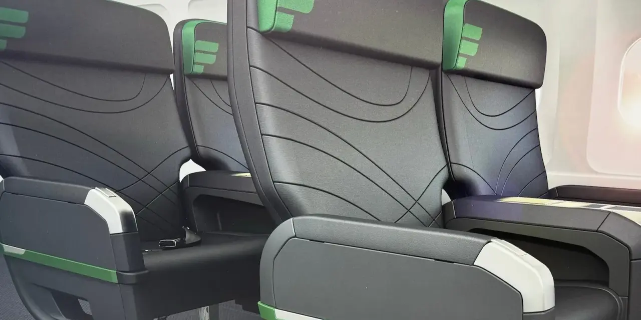 Rows of black airplane seats with green accents. Does Frontier have first class? These seats look comfortable, but it's unclear if they are first class.