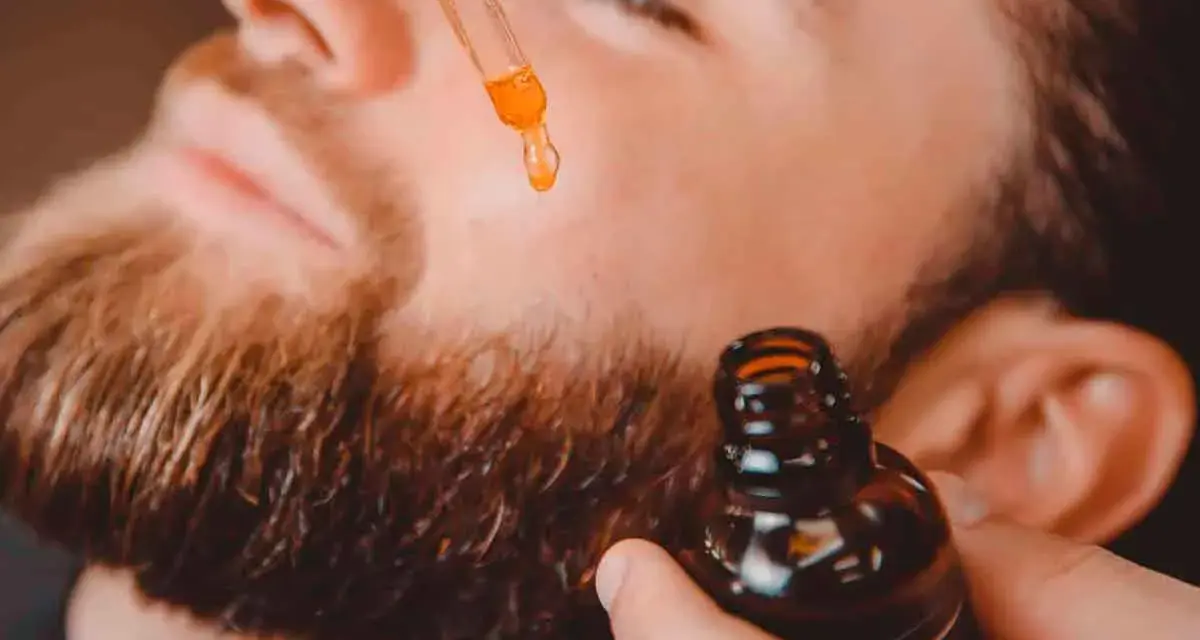 Un hombre aplica aceite con un gotero a su barba. Un secreto para tener una barba bonita y cuidada.