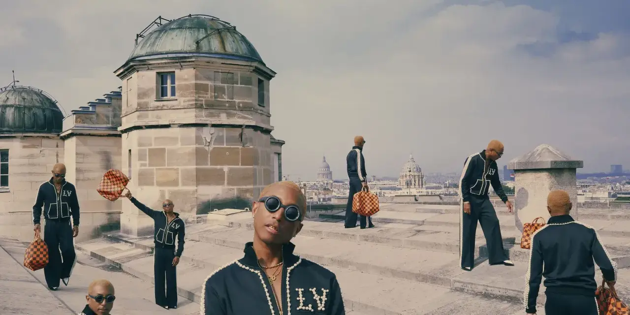 Uomini con tute Louis Vuitton e borse iconiche, un omaggio a chi era Louis Vuitton e al suo impero.