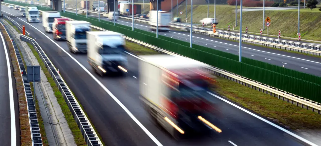 Ciężarówki na autostradzie, rozmyte przez ruch. Kierowcy potrzebują pauzy, by odpocząć od długiej jazdy.