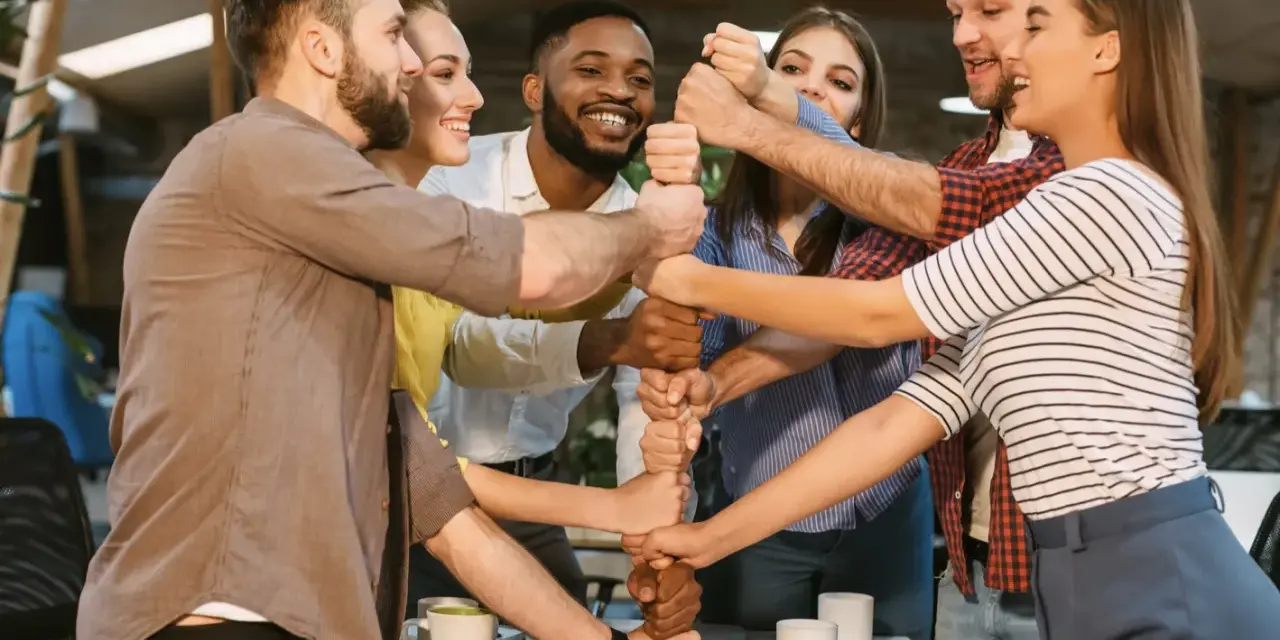 Une équipe soudée, poings serrés, symbolisant l'unité et la collaboration. Une belle idée séminaire pour renforcer la cohésion.