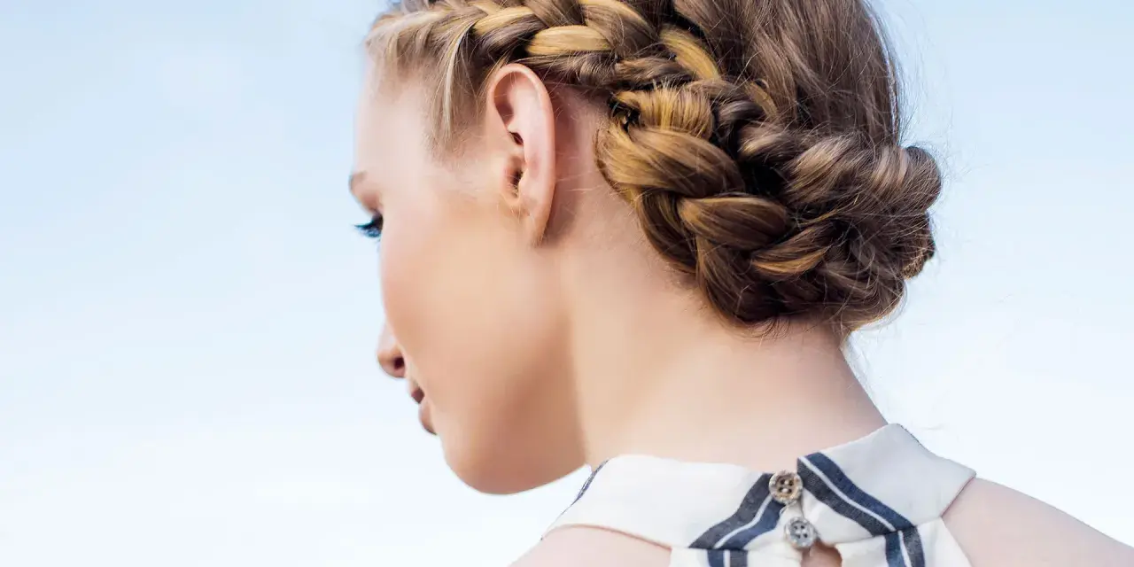 Peinados con trenzas: una mujer con un recogido trenzado elegante, ideal para un día soleado.