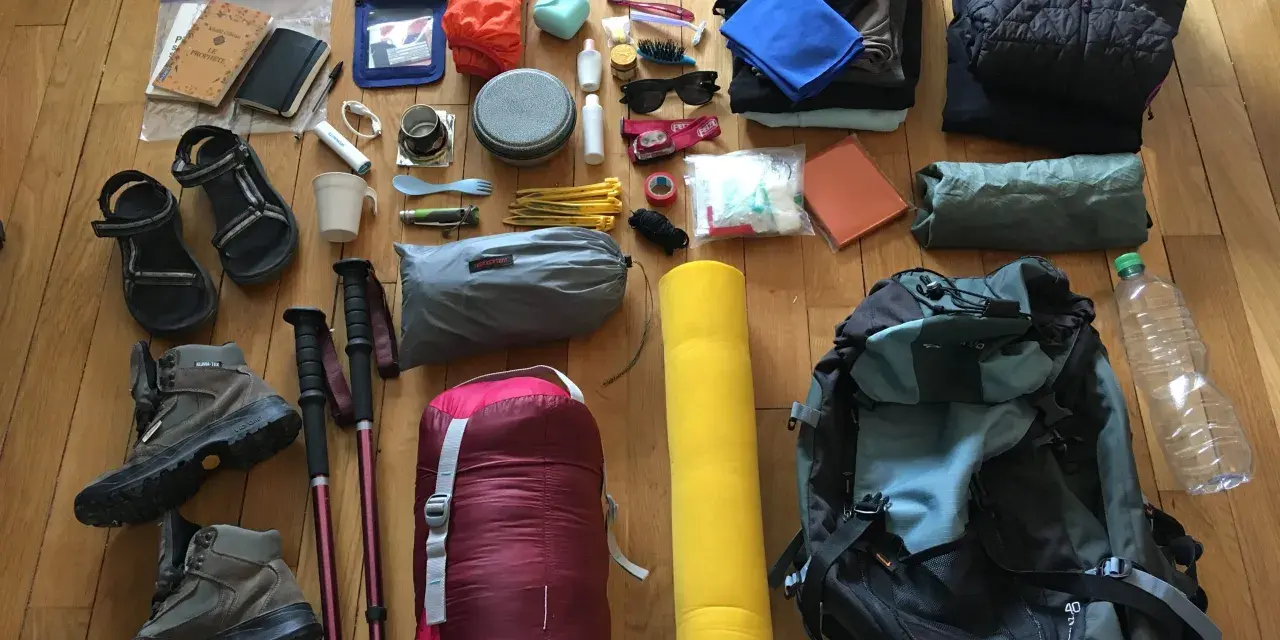 Préparatifs pour une randonnée : chaussures, bâtons, sac de couchage, sac à dos, vêtements, trousse de toilette, gourde. Voici comment ranger son sac de randonnée.