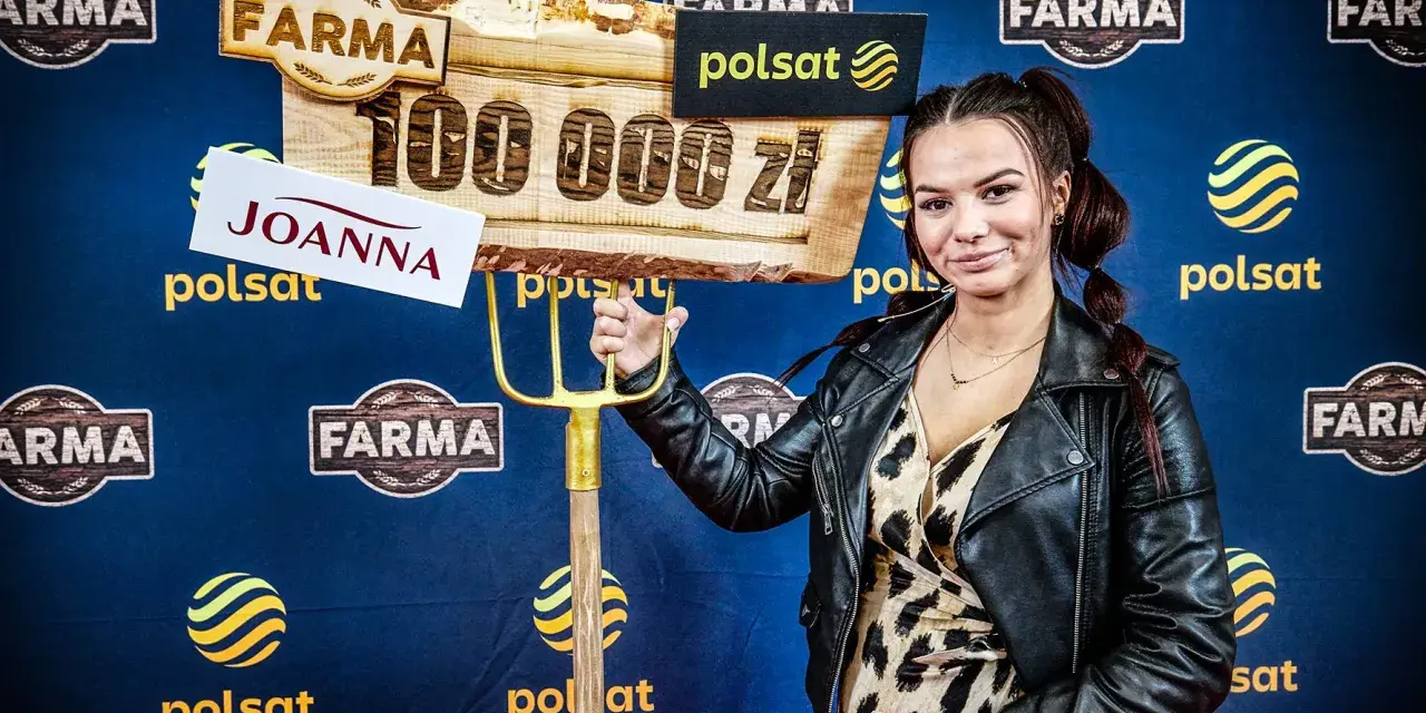 Joanna z "Farmy" trzyma widły i tablicę z napisem "100 000 zł".