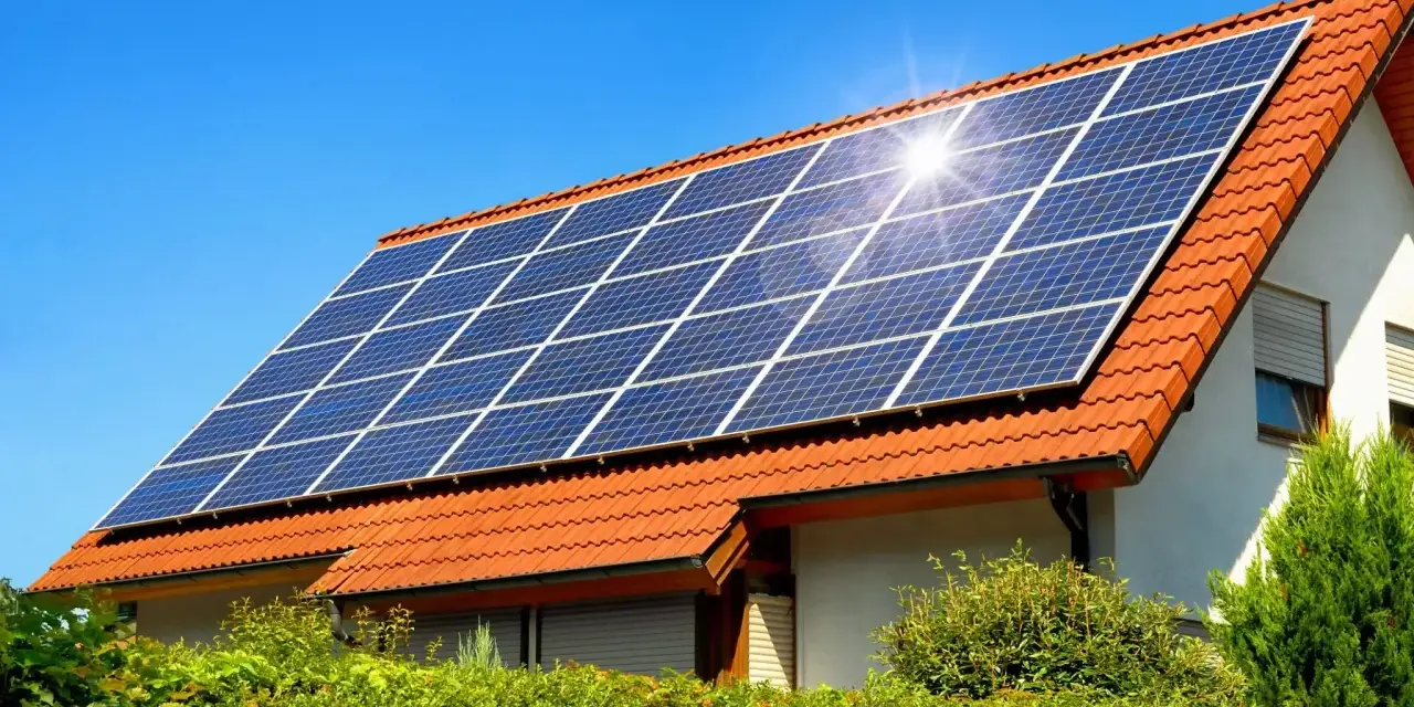 Instalacja fotowoltaiczna 10 kW cena z montażem na dachu domu pod błękitnym niebem.